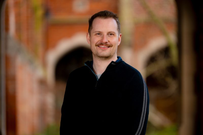 Ross Campbell headshot standing in front of red brick building